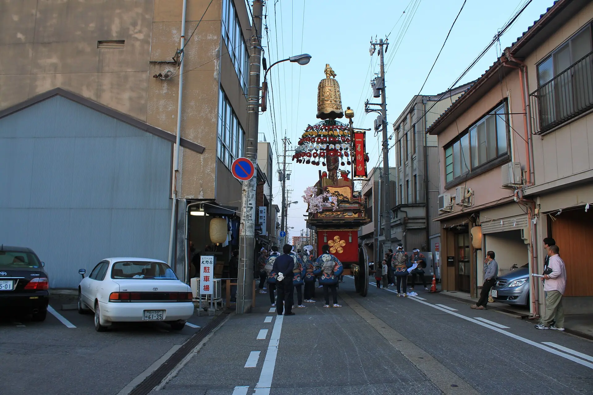 花傘と金色の鉾頭を掲げて高岡の町を進む御車山